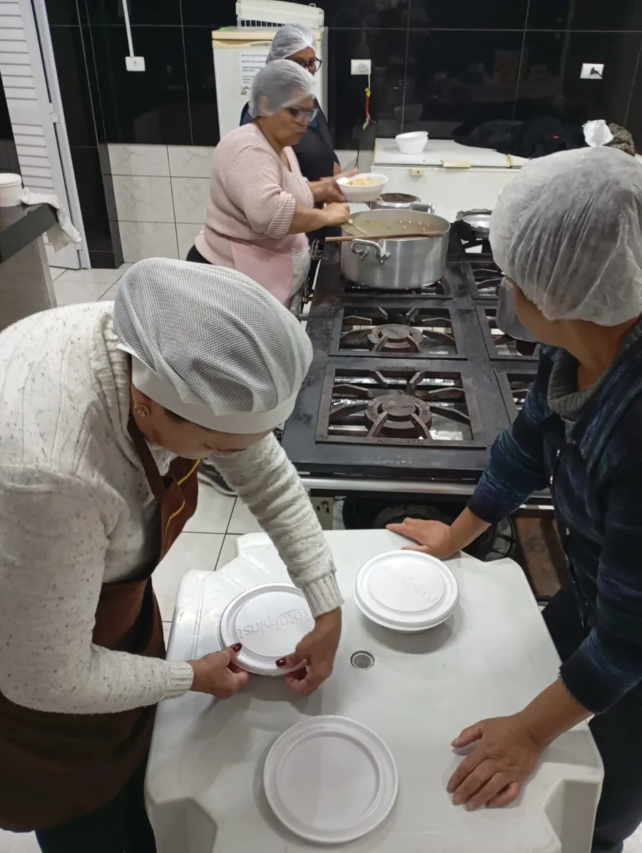 Voluntários embalando as marmitas em potes descartáveis, prontos para entrega